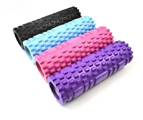 Quatre rouleaux de massage texturés alignés côte à côte, de couleur noire, bleu clair, rose et violet. Chaque rouleau présente une surface en relief avec des motifs rectangulaires pour favoriser le massage musculaire en profondeur